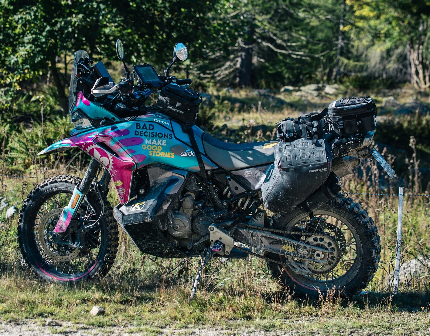 Waterproof motorcycle luggage on an adventure bike in heavy rain, showing roll-top panniers and muddy conditions